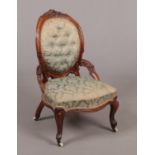 A Victorian carved walnut nursing chair. With original silk upholstery and raised on scroll