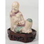 A 19th century Chinese carved soapstone figure raised on a canted rectangular hardwood plinth.
