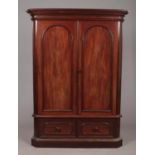 A Victorian mahogany gentleman's double wardrobe. With arched moulding to the doors and raised on