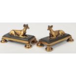 A small pair of bronze mantel figures formed as recumbent greyhounds. Each raised on a bevelled