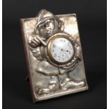 An Edwardian silver mounted oak strut clock. Embossed with a caricature of a policeman holding and