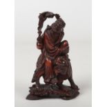A 19th century Chinese carved wood figure of a man mounted upon a lion dog. With glass inset eyes