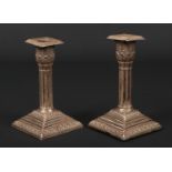 A pair of Edwardian silver dwarf candlesticks. With acanthus formed sconces raised on cluster