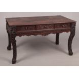 A large Chinese carved hardwood three drawer desk raised on scrolling supports, 83cm x 150cm, 85cm