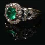 A Georgian gold and silver mounted emerald and diamond cluster ring. With a cushion cut emerald