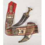 A Janbaya dagger with picquet inlaid horn grip and in scabbard on sash. The sash decorated with