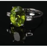 An Art Deco style 18 carat white gold peridot and diamond ring. Set with a large faceted ovoid