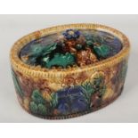 A Victorian majolica oval casserole dish and cover. With floral finial, further moulded with