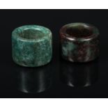 Two Chinese carved jade coloured hardstone archers rings, one with cherry suffusions. Good