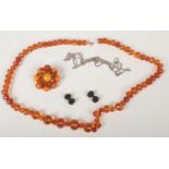 A vintage amber starburst dress brooch, an amber coloured bead brooch, a white metal neck chain