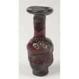 A Romanesque marbleised glass bottle vase in tones of green and red. The main body formed as the two