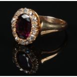 A Victorian 18 carat gold garnet and diamond cluster ring. With a large ovoid faceted purple