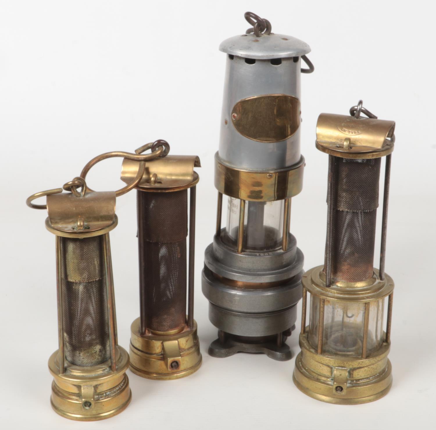 Four miners lamps. A Naylor of Wigan spiralarm, along with four brass examples one Davis of Derby