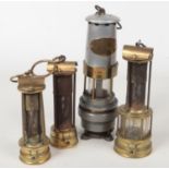 Four miners lamps. A Naylor of Wigan spiralarm, along with four brass examples one Davis of Derby