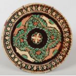 A Bombay School of Arts pottery charger. Decorated with birds and foliage on a treacle glaze, 40cm