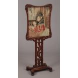 A William IV rosewood facescreen. With needlework panel depicting the portrait of a praying