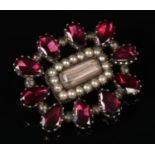 A Regency garnet and pearl mourning brooch with plait centre panel, 28mm wide. Good condition.