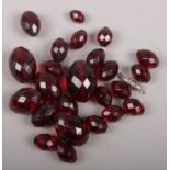 A set of graduated cherry amber coloured beads of ovoid faceted form, along with a white metal