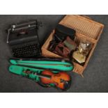 A wicker basket with contents of clocks, cameras, cased Lark violin, typewriter etc.