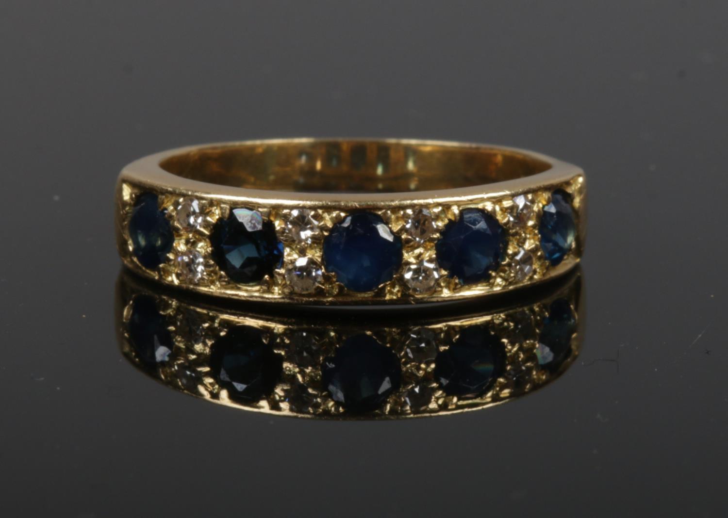 A gold, diamond and sapphire ring. Set with five sapphires interspersed with four pairs of diamonds.