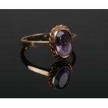 A 9ct gold and amethyst ring. With large ovoid faceted stone under rope twist border, Size O.