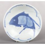 A Chinese Kangxi style blue and white dish. Painted with wide strokes of underglaze blue with a carp
