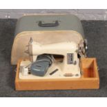 A cased vintage electric sewing machine.