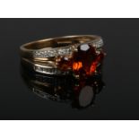 A 9ct gold ring set with a trio of three ovoid orange gemstones and with diamond shoulders. Size Q.