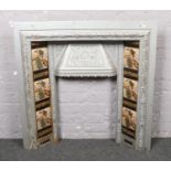 A grey painted Victorian cast iron fire surround with floral tiles.