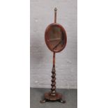 An early Victorian rosewood pole screen with oval mirror. With twist support an raised on a petal