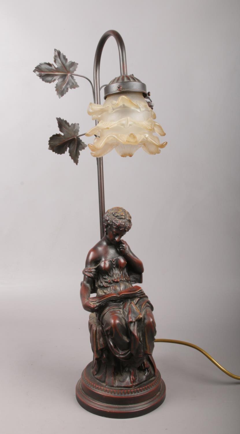 A bronzed composite figural table lamp of a lady reading.