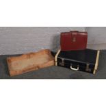 A wooden bakers tray along with a vintage suitcase and briefcase.