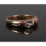 A 9ct rose gold, morganite and ruby three stone ring with rub over setting. Size R.