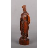 A Chinese finely carved fruitwood figure of a standing Emperor. Holding a fly swish and raised on an