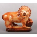 A Victorian Boness pottery figure of a lion after the Medici lions. With glass inset eyes and raised