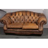 A brown leather deep buttoned two seater settee.