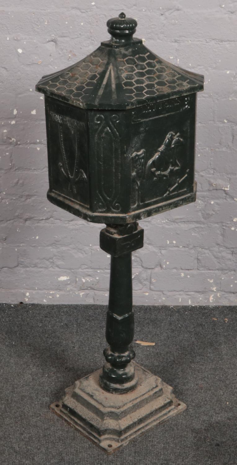 A painted cast iron post box on pedestal stand with horse racing decoration. Provenance, Lathom