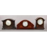 A mahogany cased dome top mantel clock inlaid with walnut and stringing. Along with two oak cased