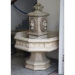 A large composition stone garden fountain. Octagonal in form and ornamented with four lion masks,