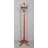 A pitch pine coat stand raised on four scroll supports, 193cm.
