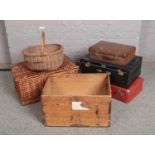 A collection of vintage suitcases, wicker baskets and a wooden crate.