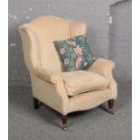 A Laura Ashley cream upholstered wing armchair in George III style.