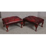 Two ox blood deep button leather footstools.