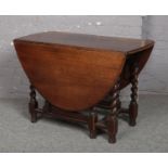 An oak gateleg dining table raised on barley twist supports, 104cm x 52cm closed, 72cm high.