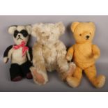 A vintage teddy bear with glower along with a vintage panda teddy and a blonde bear.