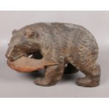 A Black Forest style carved wooden model of a bear with a fish in its jaws. Incised Chinese