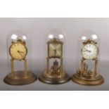 Three German brass torsion clocks under glass domes. Two marked for Jahresuhrenfabrik the other