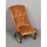 A Victorian carved mahogany nursing chair. With deep buttoned mustard velvet upholstery and raised
