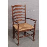 An oak rush seat ladder back kitchen armchair.