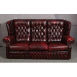 An ox blood leather deep button three seat sofa, along with a matching arm chair.